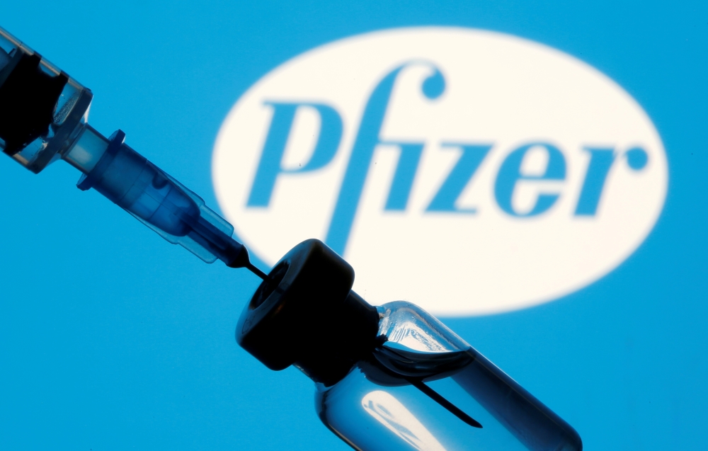 A vial and sryinge are seen in front of a displayed Pfizer logo in this illustration taken January 11, 2021. REUTERS/Dado Ruvic/Illustration/File Photo