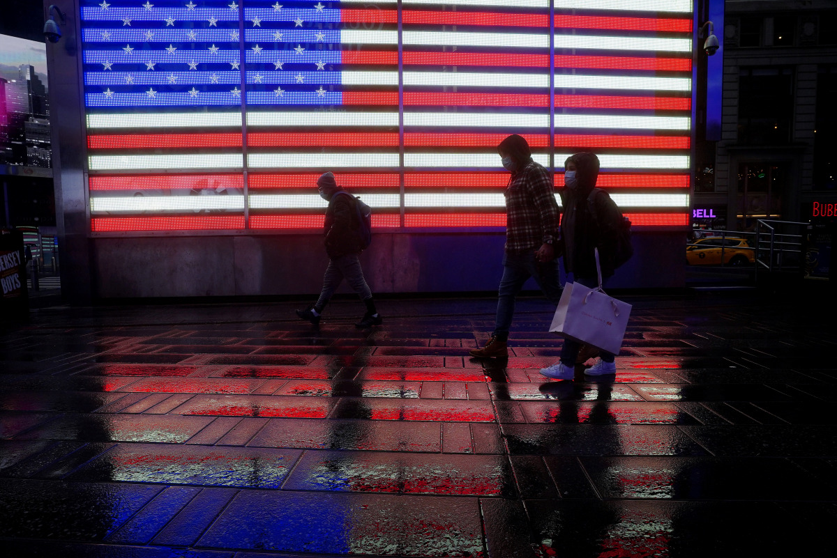 People walk in the rain in Times Square amid the coronavirus disease (COVID-19) pandemic in New York City, New York, U.S., March 18, 2021. REUTERS/Carlo Allegri
