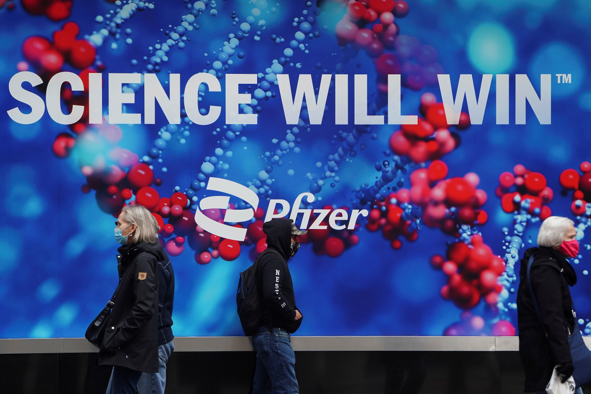 People walk past a Pfizer sign amid the coronavirus disease (COVID-19) pandemic in the Manhattan borough of New York City, New York, U.S., April 1, 2021. REUTERS/Carlo Allegri
