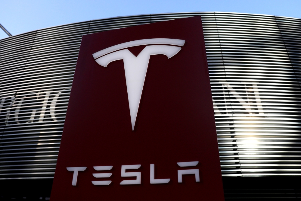 File photo: A logo of the electric vehicle maker Tesla is seen near a shopping complex in Beijing, China January 5, 2021. Reuters /Tingshu Wang/File Photo