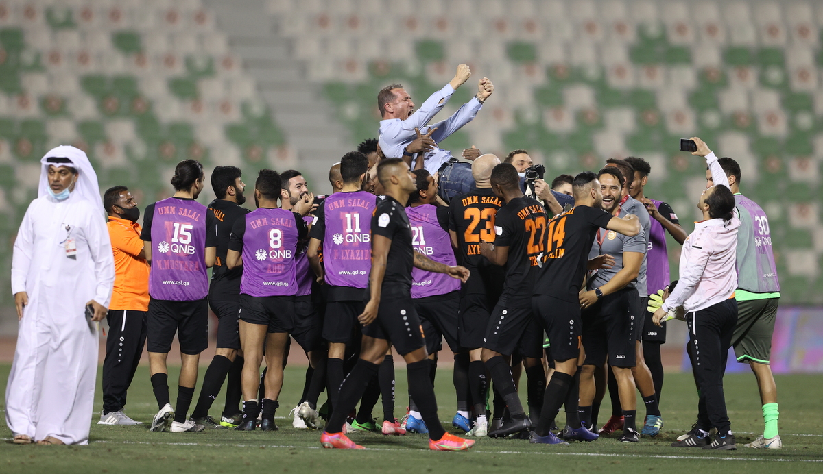 Umm Salal players celebrate with coach Ben Askar after securing their place in next season's QNB Stars League following yesterday's 1-0 win over Al Sailiya.