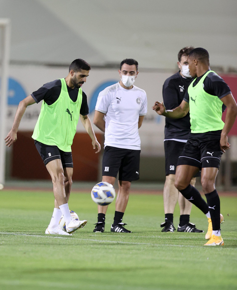 Al Sadd captain Hassan Al Haydos (left) practises with the ball as
Xavi Hernandez (second right) looks on during a training session. 