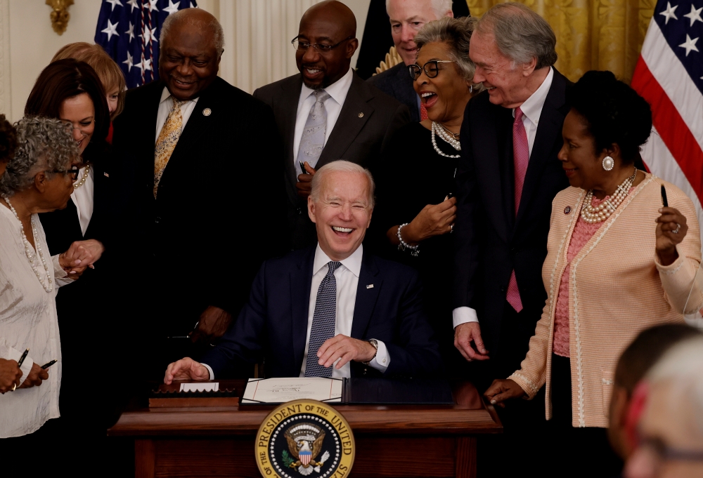 US President Joe Biden laughs with Vice President Kamala Harris and members of Congress as he signs the Juneteenth National Independence Day Act into law as Vice President Kamala Harris stands by in the East Room of the White House in Washington, U.S., Ju