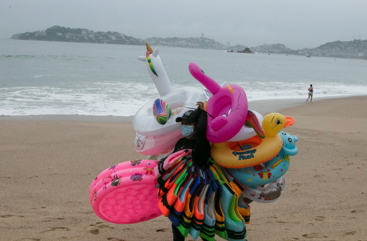 A float seller walks in Acapulco beach after storm Enrique became a hurricane off the coast of western Mexico, in Acapulco, Mexico June 26, 2021. REUTERS/Javier Verdin

