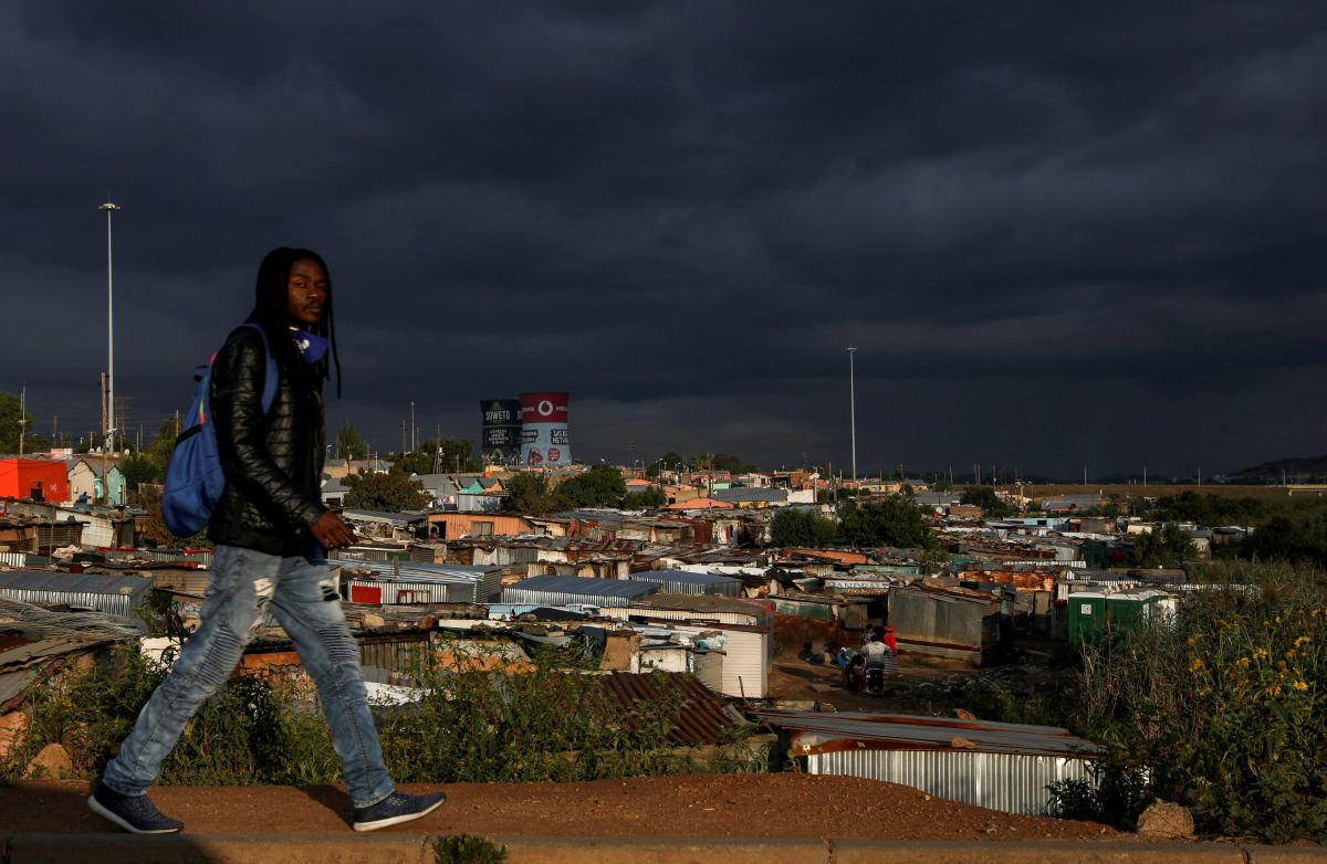 FILE PHOTO: A man walks past an informal settlement as the coronavirus disease (COVID-19) lockdown regulations ease in Soweto, South Africa, April 7, 2021. REUTERS/Siphiwe Sibeko/File Photo
