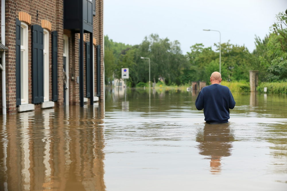 A person wades through water during a flood in Guelle, Netherlands, July 16, 2021. REUTERS/Eva Plevier