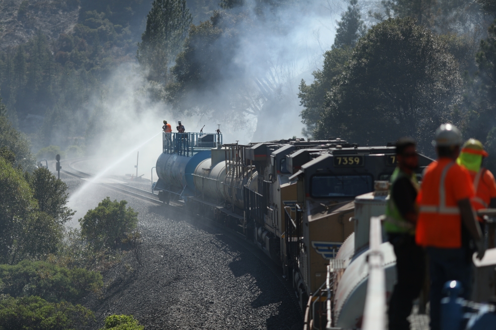 Firefighters assigned to the Union Pacific Fire Train protect the tracks and hinder the Dixie Fire from crossing the North Fork of the Feather River in Plumas National Forest, California, U.S., July 17, 2021. REUTERS/David Swanson