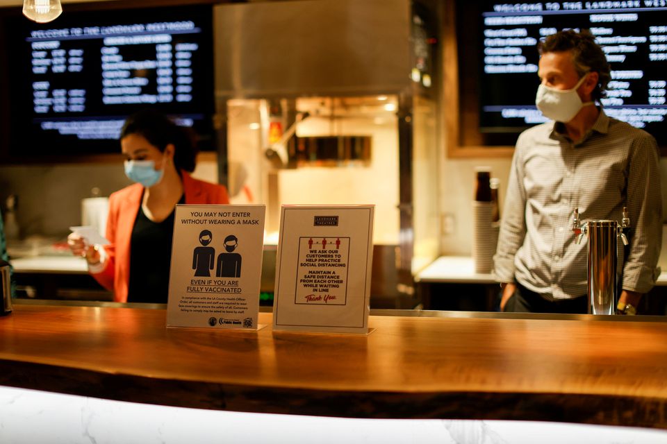 Signs advising about masks and social distancing are pictured by concessions at the Landmark Westwood theatre in Los Angeles, California, U.S., May 14, 2021. REUTERS/Mario Anzuoni/File Photo