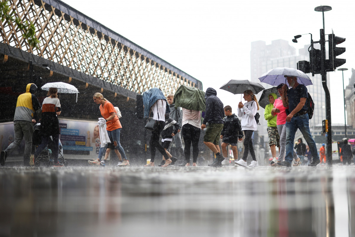 People walk through heavy rainfall, amid the coronavirus disease (COVID-19) outbreak, in London, Britain, July 25, 2021. REUTERS/Henry Nicholls
