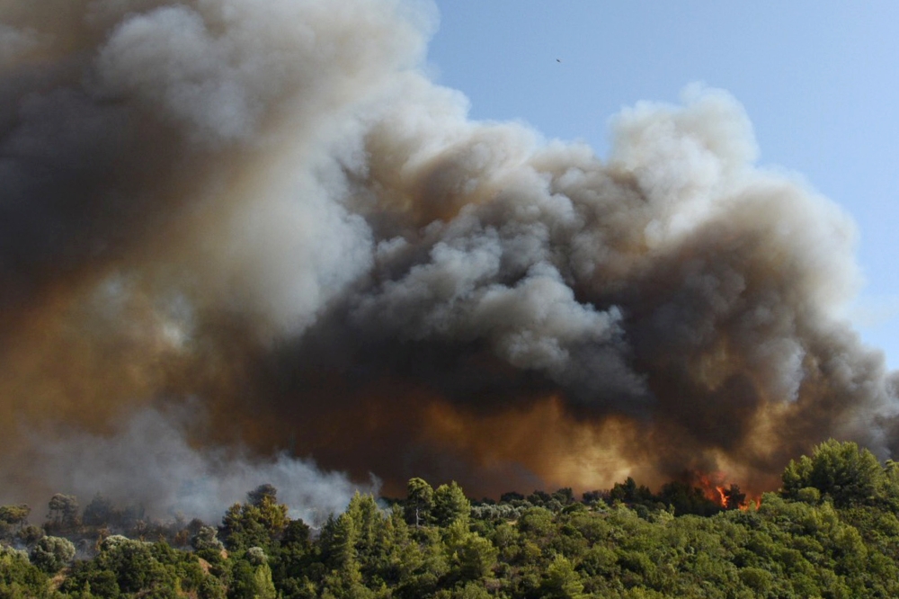 Smoke rises over trees as a wildfire burns at the village of Labiri, near Patras, Greece, July 31, 2021. (Intimenews via REUTERS)