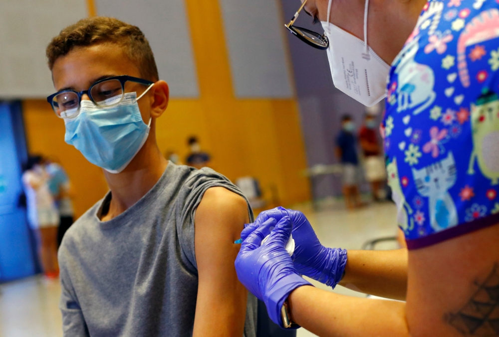 A nurse administers the first dose of the Moderna vaccine against coronavirus disease (COVID-19) to 14-year-old Jorge Hernandez at a vaccination centre in Meloneras on the island of Gran Canaria, Spain, July 28, 2021. REUTERS/Borja Suarez/File Photo