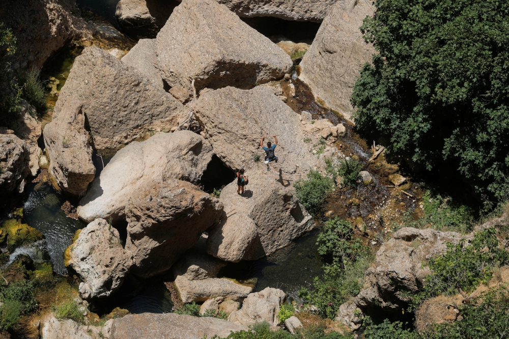 Tourists walk on the rocks of a river under the New Bridge (Puente Nuevo) amid the coronavirus disease (COVID-19) outbreak in Ronda, southern Spain, August 3, 2021. REUTERS/Jon Nazca