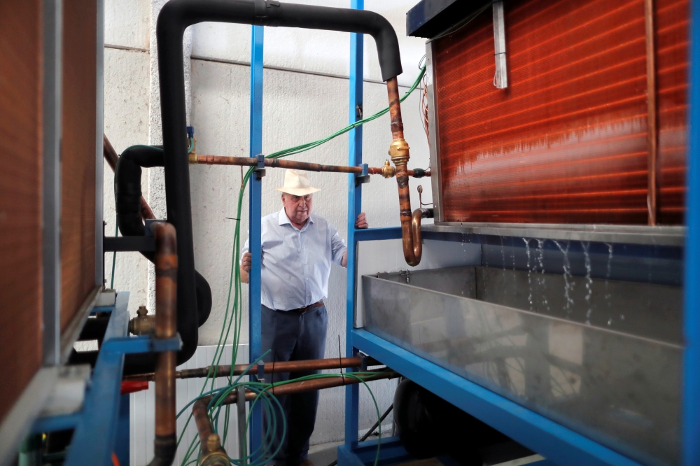 Spanish Aquaer company engineer and inventor, Enrique Veiga, 82, checks the first start-up of a machine which he invented to extract drinking water from thin air, in Carrion de los Cespedes, near Seville, Spain July 28, 2021. Picture taken July 28, 2021. 