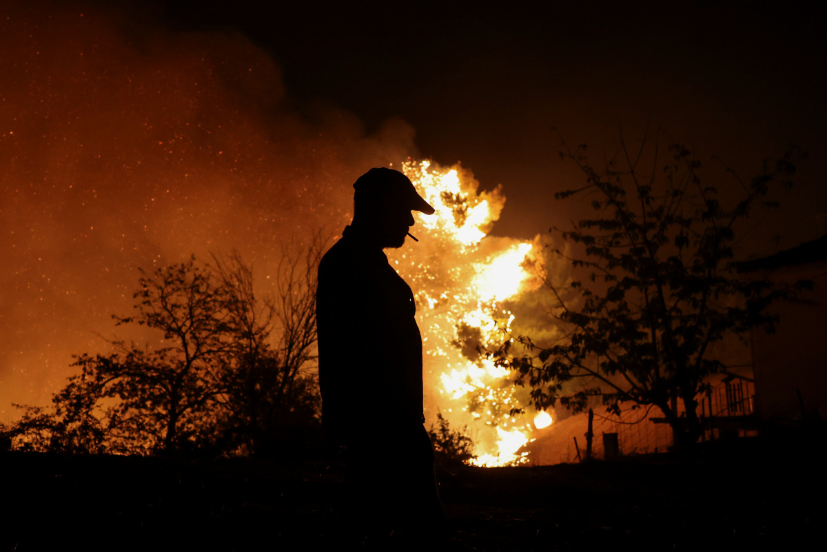 A man is silhouetted as he watches a wildfire burning in the village of Lasdikas near ancient Olympia, Greece, August 5, 2021. Picture taken August 5, 2021. REUTERS/Giorgos Moutafis
