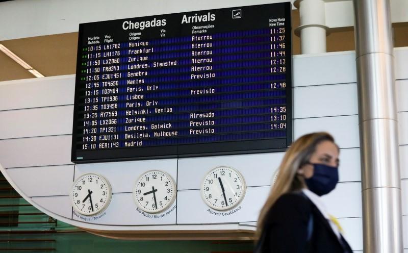 FILE PHOTO: A woman walks by the arrivals information board at Porto Airport on the first day that tourists from Britain and most EU countries are allowed to enter Portugal without needing to quarantine, as coronavirus disease (COVID-19) restrictions cont