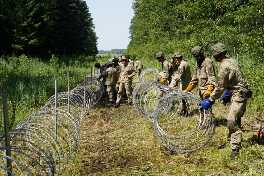 Lithuanian army soldiers install razor wire along the border with Belarus, in Druskininkai, Lithuania, July 9, 2021. Reuters/Janis Laizans/File Photo