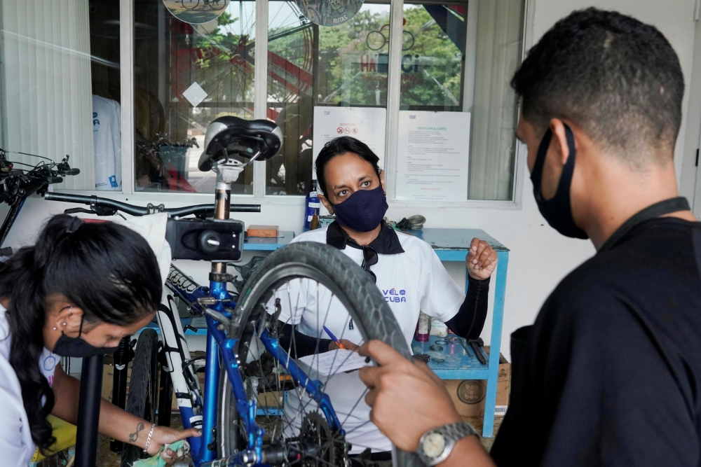 Nayvis Dias (C), founder of Velo Cuba, speaks to employees at her bicycle repair and rental company in Havana, Cuba, August 25, 2021. Picture taken on August 25, 2021. REUTERS/Alexandre Meneghini