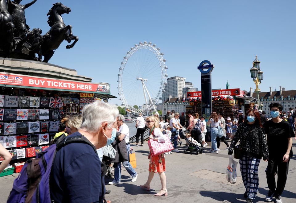 People wearing protective masks walk on Westminster Bridge, with the London Eye in the background, in London, Britain, June 1, 2021. REUTERS/John Sibley/File Photo
