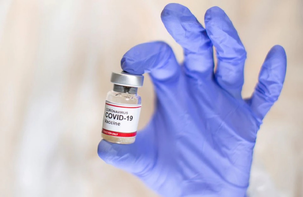 A woman holds a small bottle labelled with a 