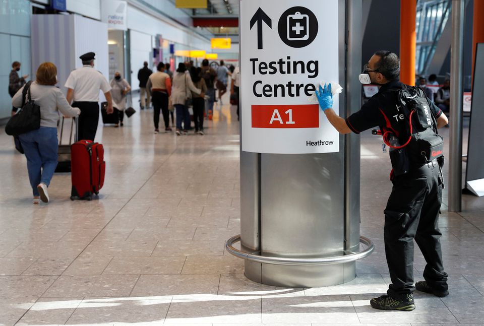 A worker sanitises a sign at the International arrivals area of Terminal 5 in London's Heathrow Airport, Britain, August 2, 2021. REUTERS/Peter Nicholls/Files
