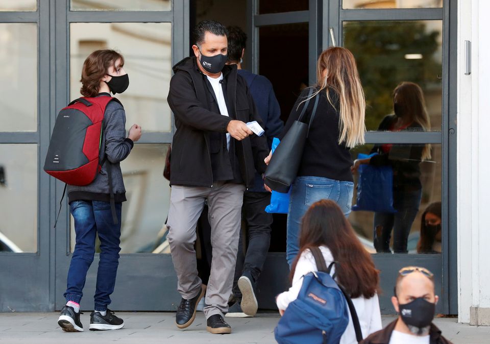 An employee checks the temperature of a woman at the entrance to a school, amid a rise in coronavirus disease (COVID-19) cases , in Buenos Aires, Argentina April 19, 2021. REUTERS/Agustin Marcarian

