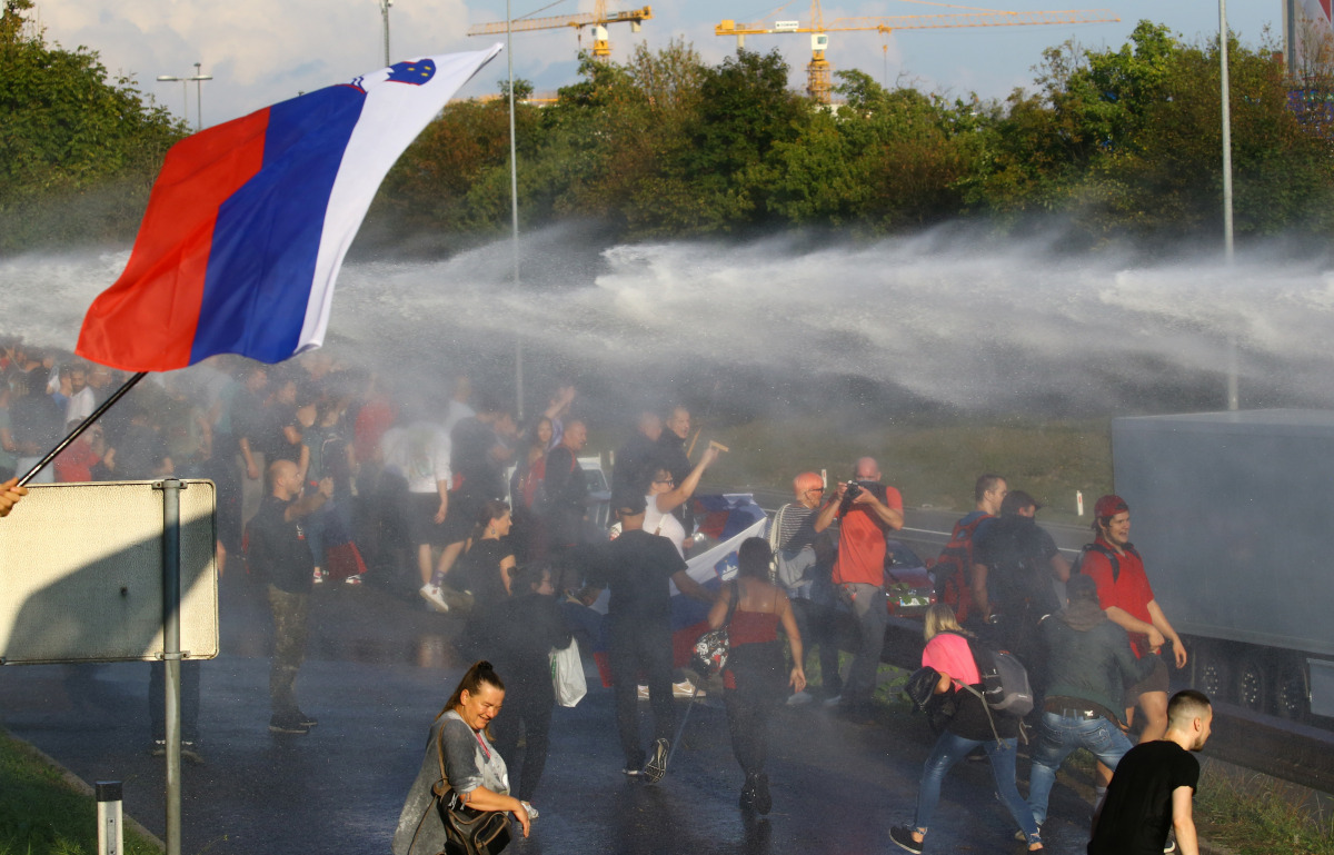 Protesters get hit by a water cannon during a protest against the coronavirus disease (COVID-19) restrictions from the government, in Ljubljana, Slovenia, September 29, 2021. REUTERS/Borut Zivulovic
