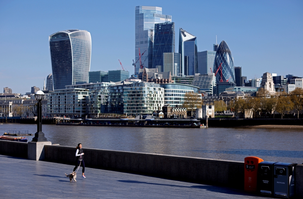 A woman exercises with a dog near the City of London financial district, in London, Britain, April 30, 2021. REUTERS/John Sibley/File Photo