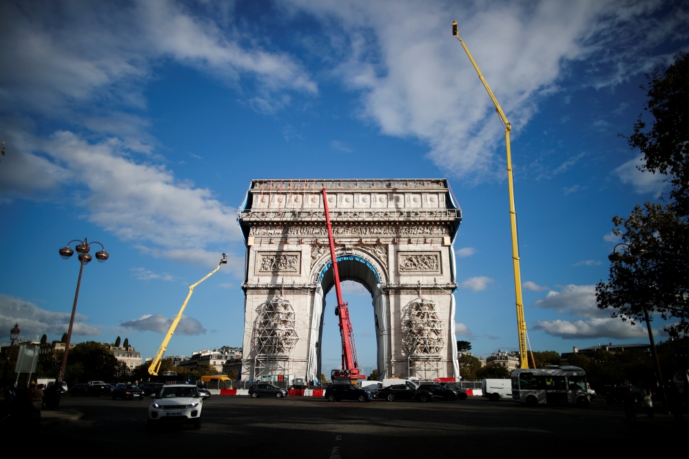 Rope access technicians work on the removal of the fully wrapped Arc de Triomphe monument, after it was wrapped for an art installation entitled 'L'Arc de Triomphe, Wrapped' conceived by the late artists Christo and Jeanne-Claude, on the Champs-Elysees av
