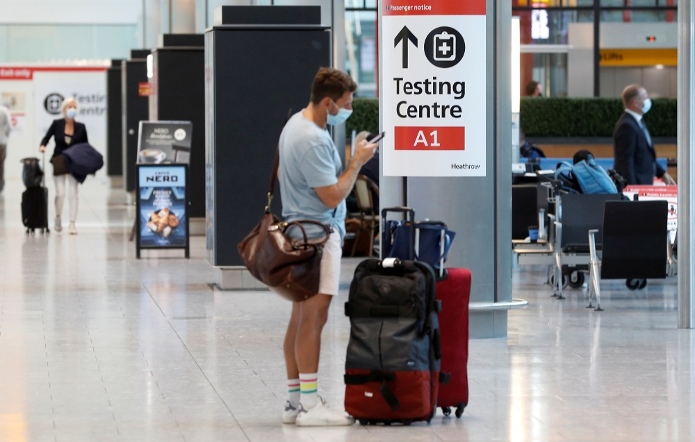 A passenger stands next to a COVID-19 testing centre sign in the International arrivals area of Terminal 5 in London's Heathrow Airport, Britain. (REUTERS/Peter Nicholls/File Photo)