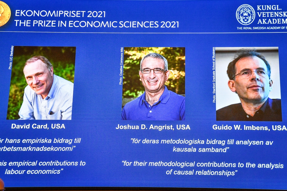 Photographs of the 2021 Nobel economics prize winners David Card, Joshua Angrist and Guido Imbens appear on a screen during the announcement of the award at a news conference at the Royal Swedish Academy of Sciences in Stockholm, Sweden, October 11, 2021.