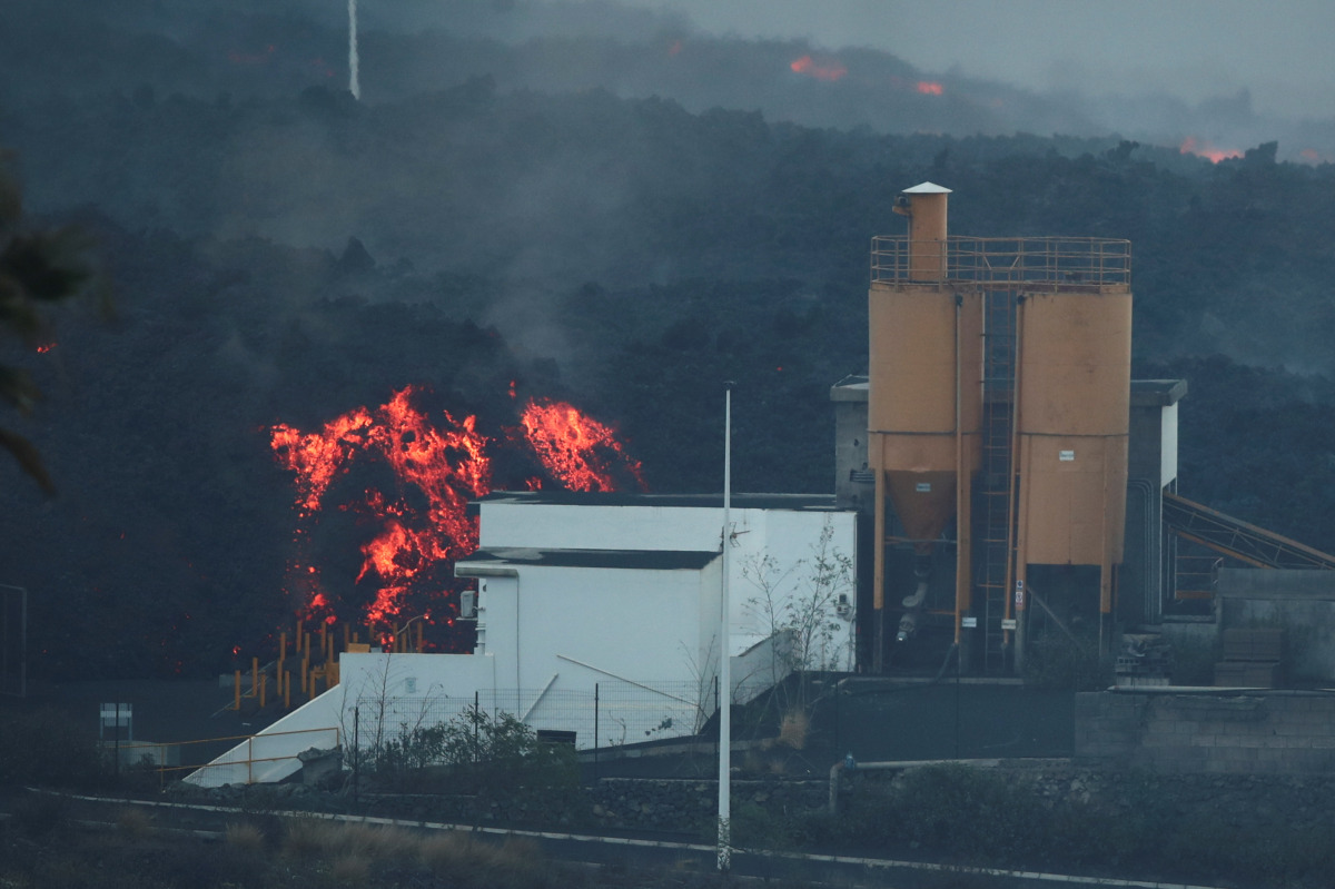 Lava rolls down behind a cement factory in Los Llanos as the Cumbre Vieja volcano continues to erupt on the Canary Island of LA PALMA, as seen from Tajuya, Spain, October 11, 2021. REUTERS/Sergio Perez
