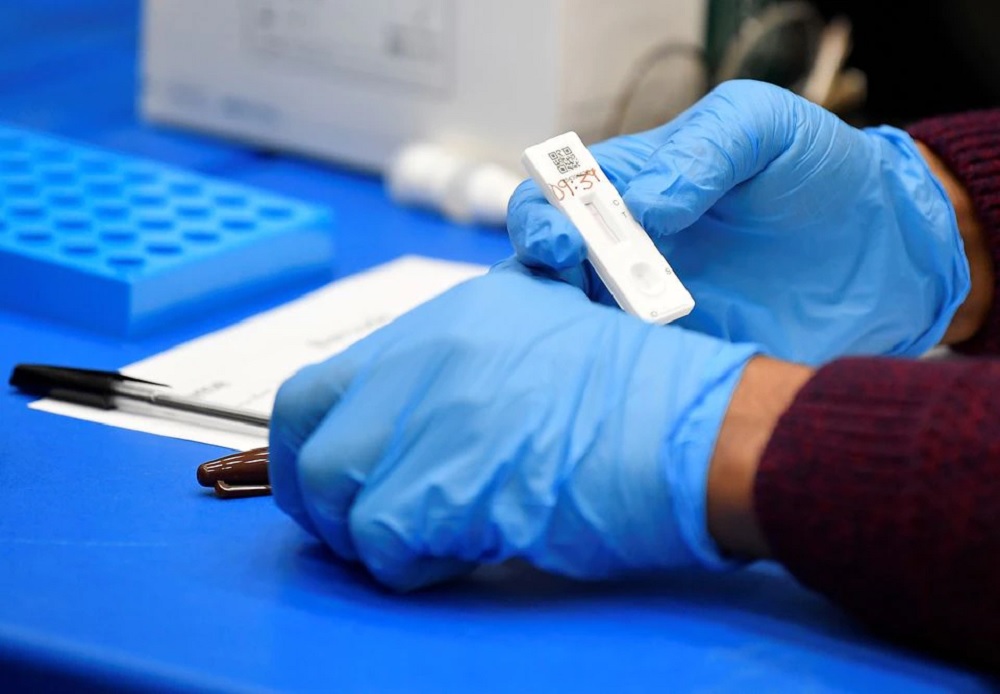 Health workers and volunteers handle lateral flow test samples and record results as students take coronavirus disease (COVID-19) tests in London, March 5, 2021. REUTERS/Toby Melville/File Photo