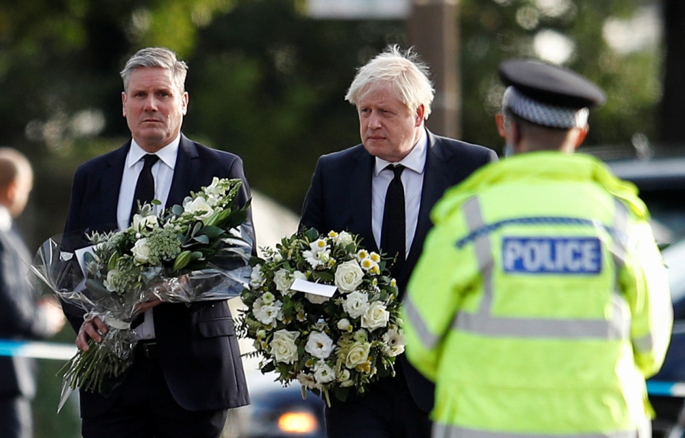 Britain's Labour Party leader Keir Starmer and Prime Minister Boris Johnson hold flowers as they arrive at the scene where British MP David Amess was stabbed to death during a meeting with constituents at the Belfairs Methodist Church, in Leigh-on-Sea, Br