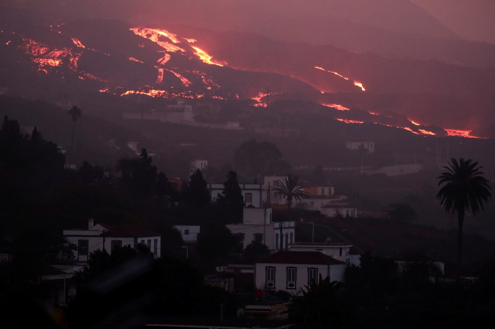 Lava spewed by the Cumbra Vieja volcano flows down a hill as the volcano continues to erupt on the Canary Island of La Palma, as seen from Tajuya, Spain, October 16, 2021. REUTERS/Sergio Perez