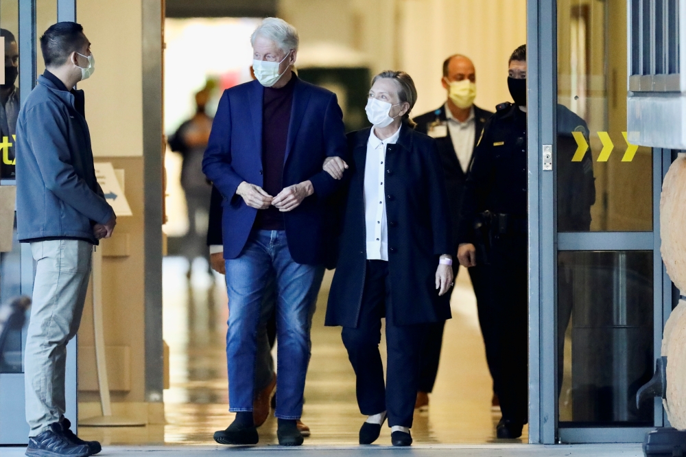 Former U.S. President Bill Clinton, accompanied by his wife, former Secretary of State Hillary Clinton, walks out of University of California Irvine Medical Center, in Orange, California, U.S. October 17, 2021. REUTERS/David Swanson
