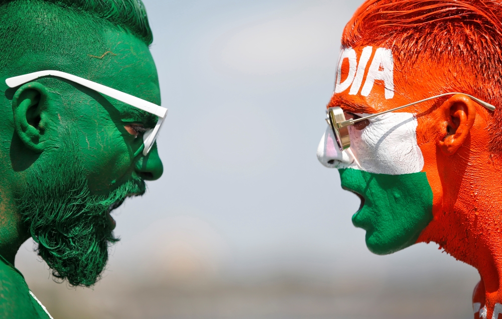 Cricket fans, with their faces painted in the Indian and Pakistani national flag colours, pose for a picture ahead of the first match between India and Pakistan in Twenty20 World Cup super 12 stage in Dubai, in Ahmedabad, India, October 23, 2021. Reuters/