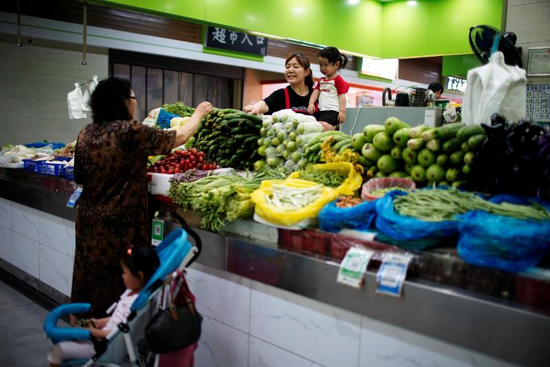 FILE PHOTO: Two grandmothers with their granddaughter trade vegetables at a market on the outskirts of Shanghai, China June 3, 2021. REUTERS/Aly Song