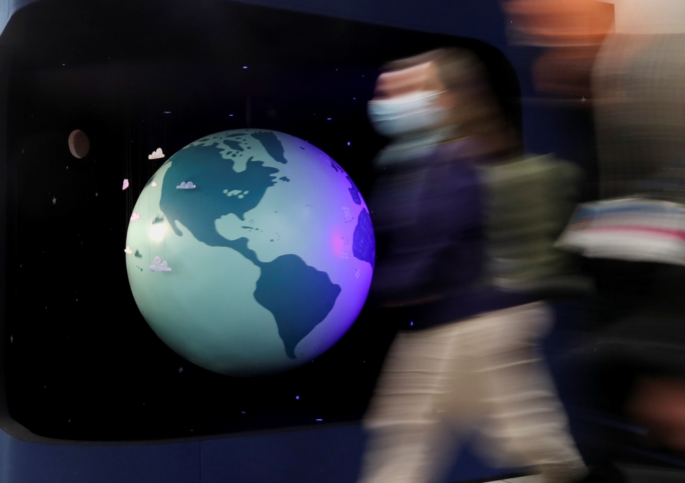 People walk past a mode of the earth during the UN Climate Change Conference (COP26) in Glasgow, Scotland, Britain, October 31, 2021. REUTERS/Yves Herman