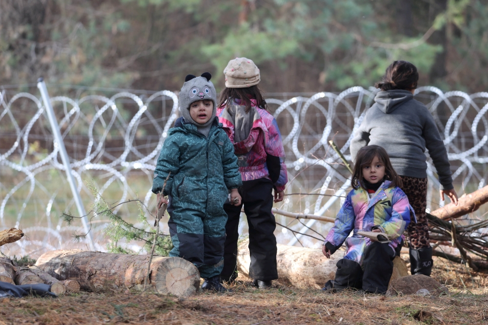 FILE PHOTO: Children gather near a barbed wire fence in a migrants' makeshift camp on the Belarusian-Polish border in the Grodno region, Belarus November 12, 2021. Ramil Nasibulin