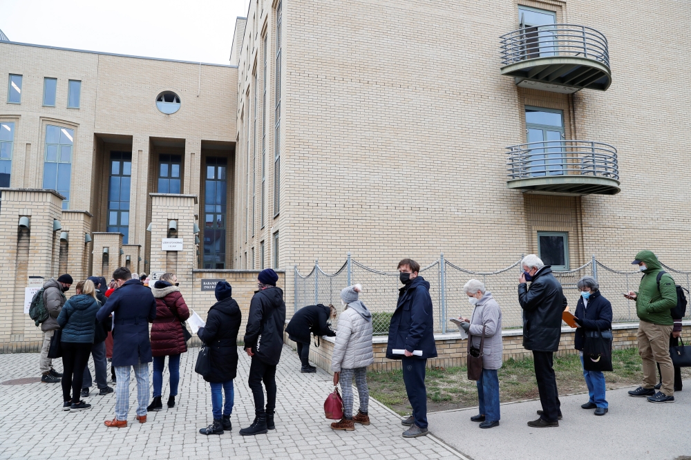 People stand in a queue for vaccination in front of a hospital as the spread of the coronavirus disease (COVID-19) continues, in Budapest, Hungary, November 22, 2021. REUTERS/Bernadett Szabo