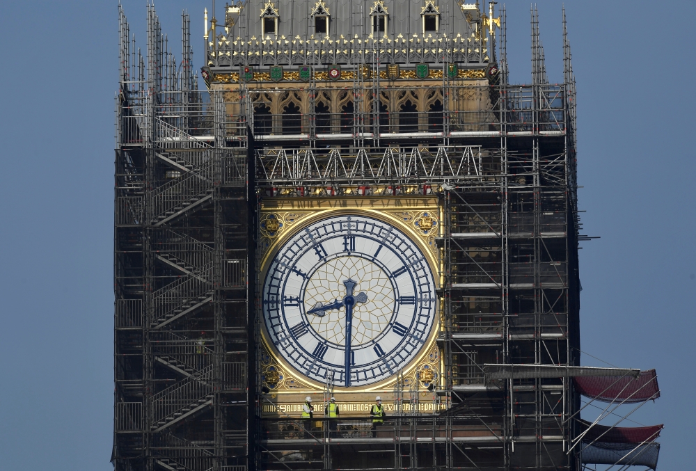 Workers stand on scaffolding underneath one of the clock faces on the Elizabeth Tower, more commonly known as Big Ben, as hands and dials are seen restored to the original Prussian blue colouring, whilst renovation works continue at the Houses of Parliament, London, Britain, September 6, 2021. REUTERS/Toby Melville/File Photo