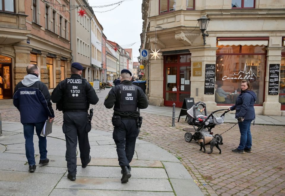 A member of the public order office is accompanied by police officers as he checks the coronavirus disease (COVID 19) 