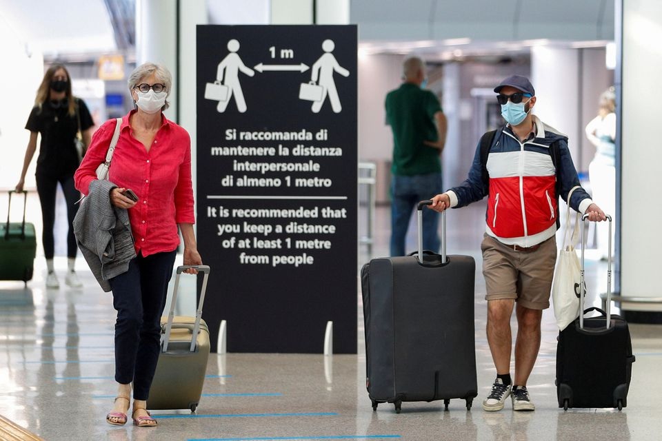 Passengers wearing protective face masks walk at Fiumicino Airport on the day EU governments agreed a 