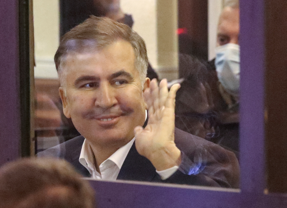Georgian former President Mikheil Saakashvili, who was convicted in absentia of abuse of power during his presidency and arrested upon his return from exile, waves inside a defendant's dock during a court hearing in Tbilisi, Georgia, November 29, 2021. REUTERS/Irakli Gedenidze/Pool