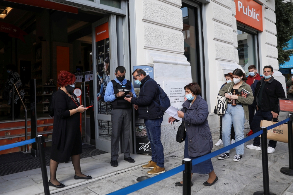 A shop employee checks customers’ vaccination certificates against the coronavirus disease (COVID-19), as the government imposed further measures for unvaccinated citizens, in Athens, Greece, November 22, 2021. REUTERS/Louiza Vradi/File Photo