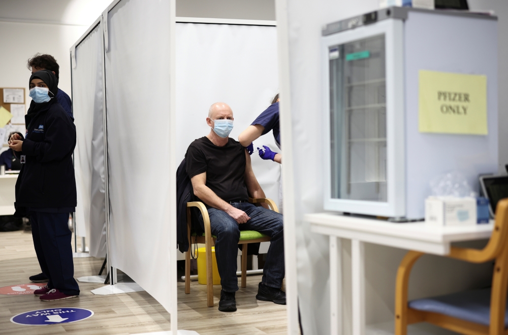 A person receives a dose of the Pfizer coronavirus disease (COVID-19) vaccine at a vaccination site at the Westfield shopping centre in London, Britain, December 3, 2021. REUTERS/Henry Nicholls