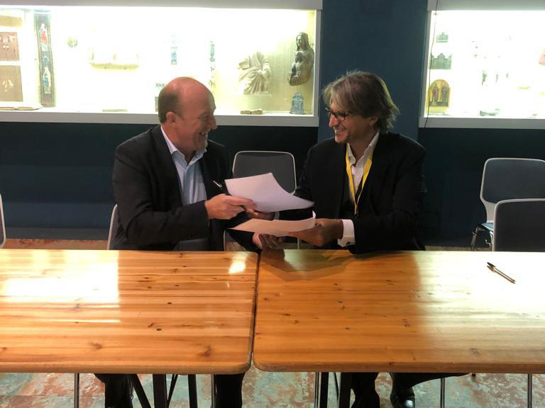Chairman of Sport at the Service of Humanity David Eades and CEO of Save the Dream Massimiliano Montanari exchange documents during the MoU signing ceremony.