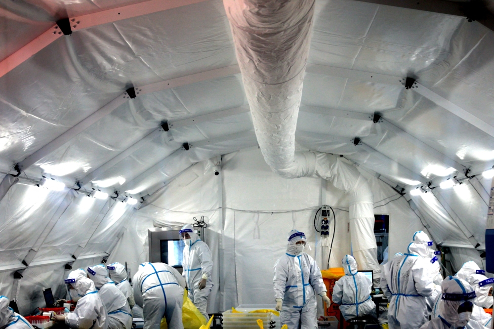Medical workers in protective suits work inside a makeshift nucleic acid testing laboratory set up at a convention centre following the coronavirus disease (COVID-19) outbreak in Xian, Shaanxi province, China December 22, 2021. cnsphoto via Reuters