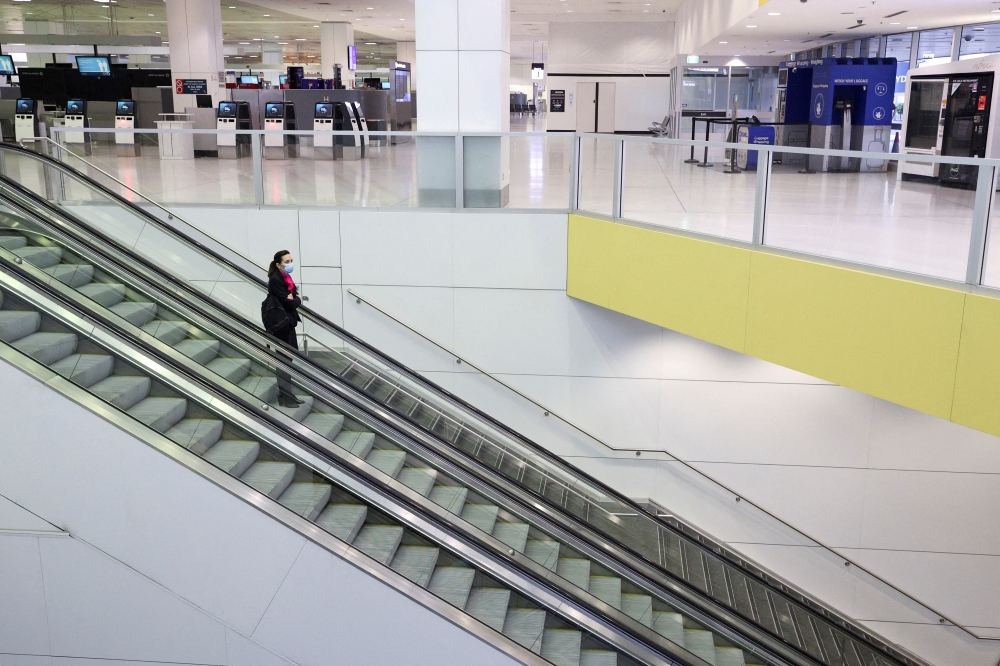 A flight crew member stands on an escalator in the international terminal at Sydney Airport, as countries react to the new coronavirus Omicron variant amid the coronavirus disease (COVID-19) pandemic, in Sydney, Australia, November 30, 2021. REUTERS/Loren Elliott/File Photo