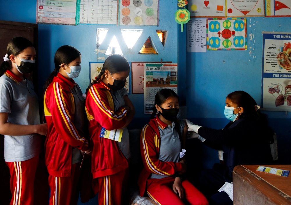 Students wait in a queue as their friend receives a dose of the Moderna vaccine at their school against the coronavirus disease (COVID-19), during a vaccination drive for children aged 12-17 in Bhaktapur, Nepal, January 9, 2022. REUTERS/Navesh Chitrakar
 